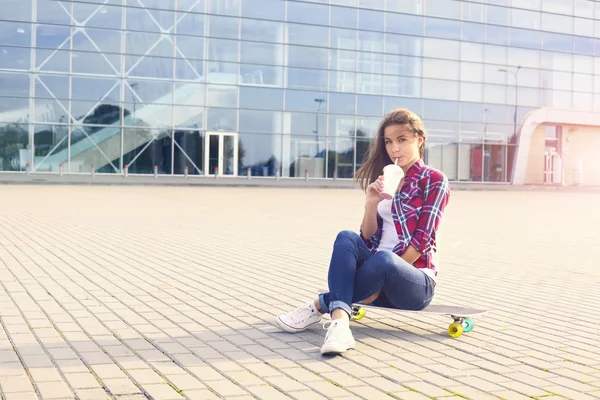 Bella giovane donna con uno skateboard e frullato — Foto Stock