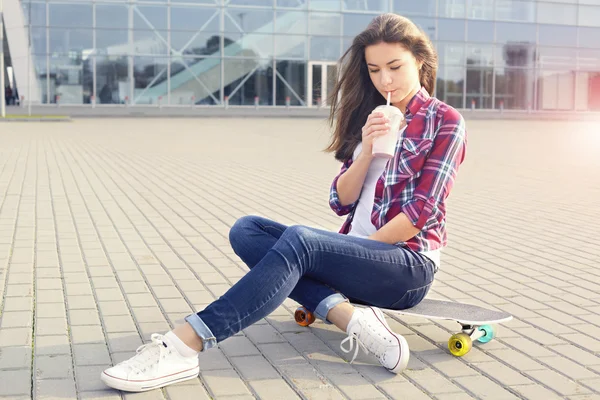 Krásná mladá žena s skateboard a koktejl — Stock fotografie