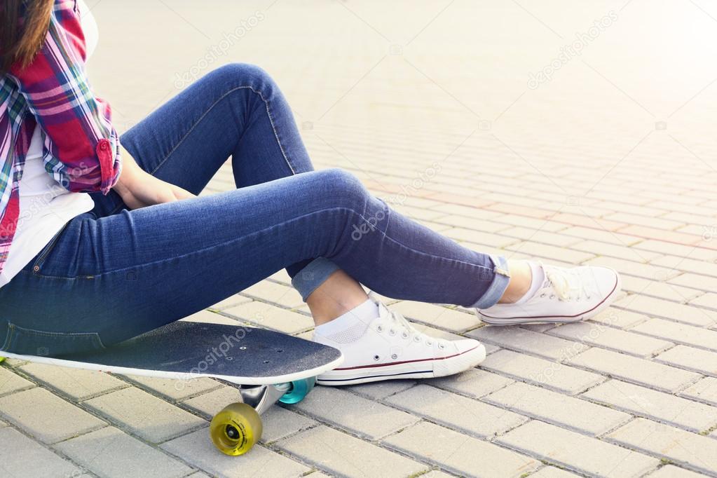 Beautiful young sitting on skateboard close up