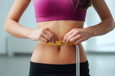 Slim woman measuring her thin waist clipart