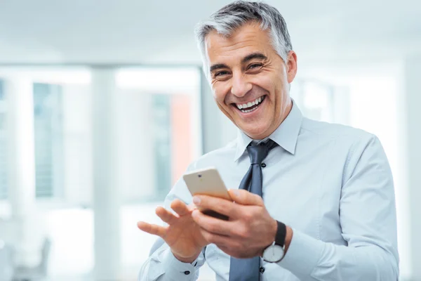 Empresário sorridente usando um telefone inteligente — Fotografia de Stock