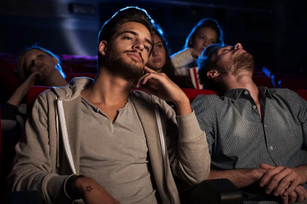 Giovani che guardano un film noioso al cinema — Foto Stock