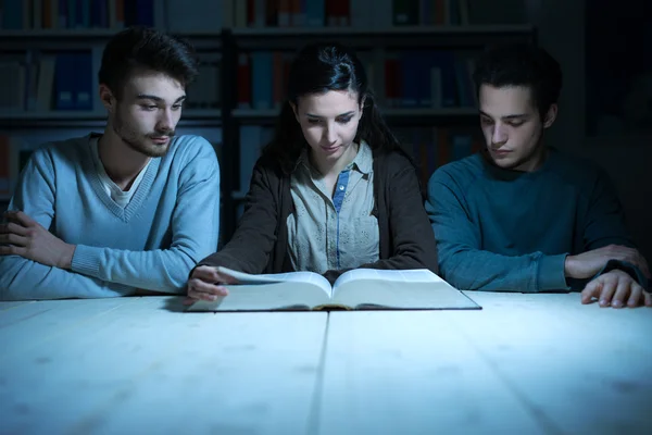 Jóvenes estudiantes leyendo un libro tarde en la noche — Foto de Stock