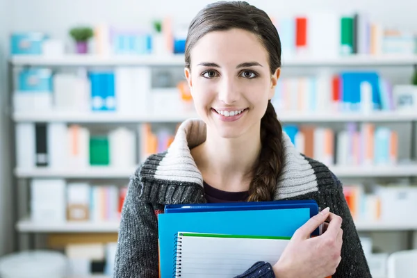 Estudante sorrindo segurando cadernos — Fotografia de Stock