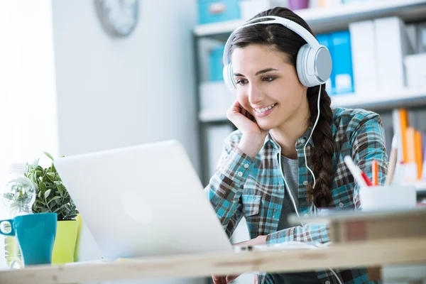 Chica con auriculares usando un ordenador portátil — Foto de Stock