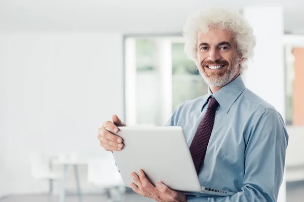 Uomo d'affari fiducioso che tiene un computer portatile — Foto Stock