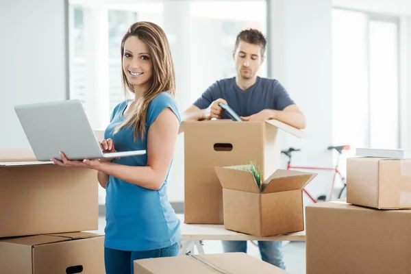 Pareja usando un portátil en su nueva casa — Foto de Stock