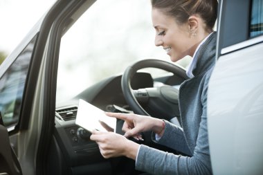 Tablet ile bir arabada gülümseyen kadın