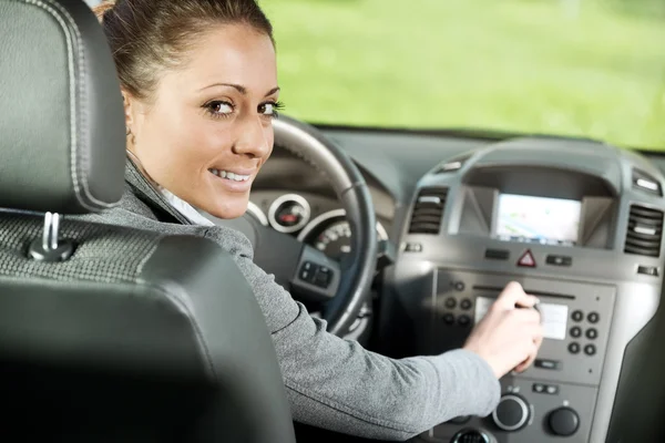 Mujer ajustando el volumen de radio en el coche — Foto de Stock