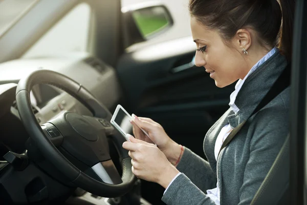 Femme souriante dans une voiture avec tablette — Photo