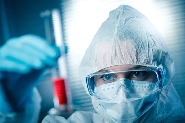 Investigador en traje de materiales peligrosos con tubo de ensayo — Foto de Stock