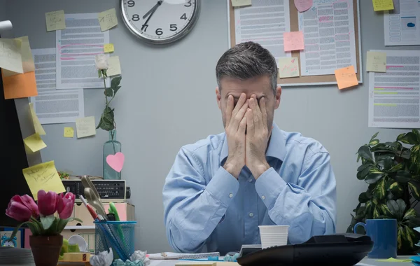 Tired office worker with head in hands — Stock Photo, Image