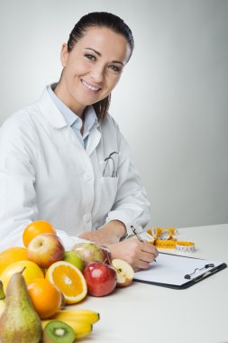Smiling nutritionist writing medical records clipart