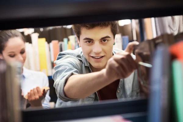 Студенти шукають книги в бібліотеці — стокове фото