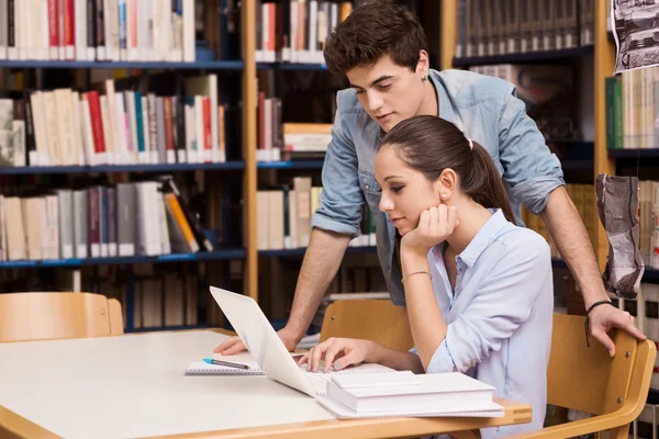 Colegas de escola estudando juntas na biblioteca — Fotografia de Stock