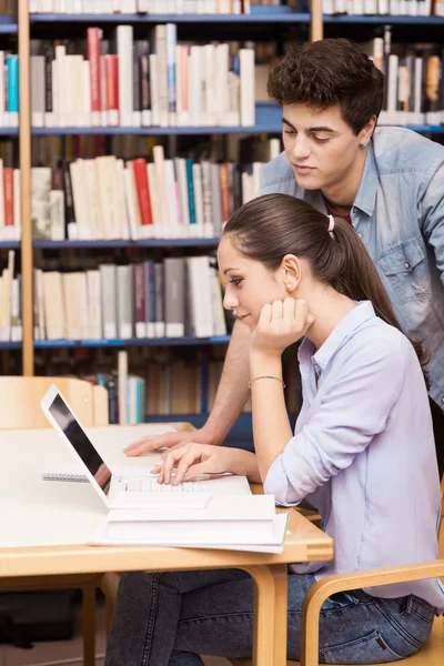 Compañeros de escuela estudiando juntos en la biblioteca — Foto de Stock