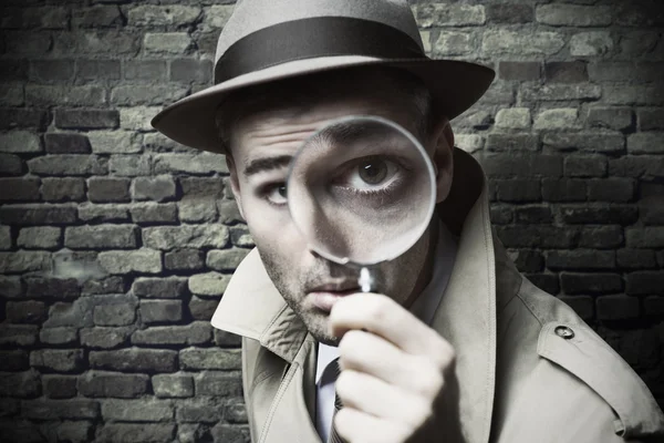 Vintage detective looking through a magnifier — Stock Photo, Image