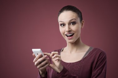 Surprised young woman using mobile phone clipart