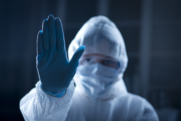 Female scientist in protective hazmat suit with hand raised