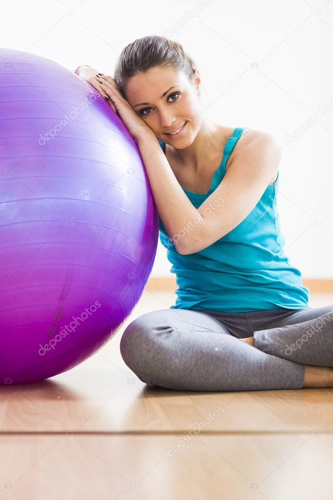 Young woman exercising with physioball at gym