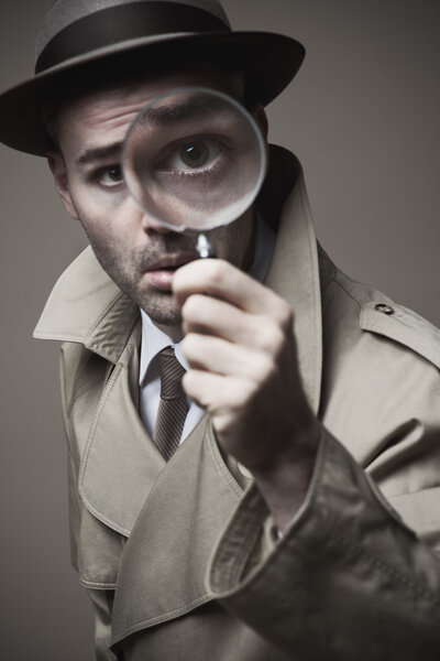 Vintage detective looking through a magnifier