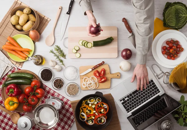 Mann kocht mit Laptop — Stockfoto