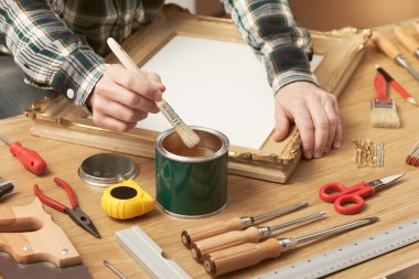 Decorator varnishing a wooden frame clipart