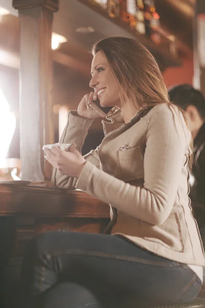 Mujer sonriente en el bar teniendo una llamada telefónica — Foto de Stock