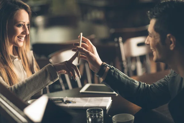 Modisches Paar an der Bar mit dem Smartphone Stockbild