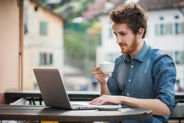 Joven conectándose con un portátil en el bar — Foto de Stock