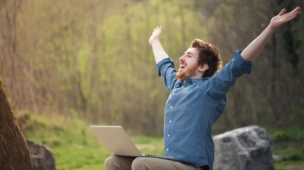 Happy hipster with laptop in the forest — Stock Photo, Image
