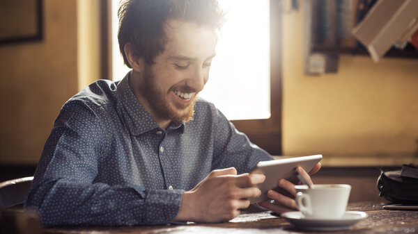 Cheerful hipster social networking with his tablet