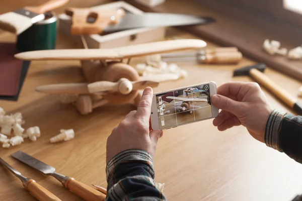 Homme photographiant son jouet en bois fait main — Photo