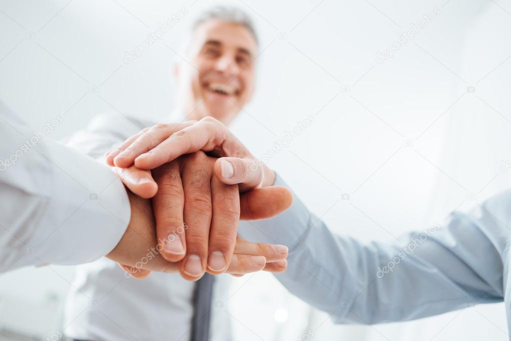 Cheerful business people stacking hands