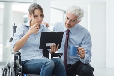 Businessman showing a document to a woman in wheelchair