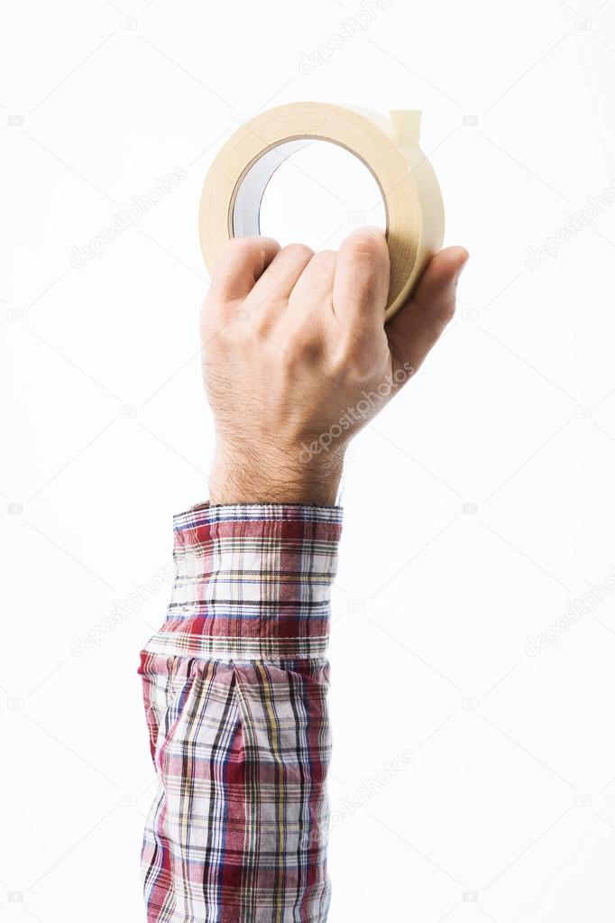Hand holding a roll of masking tape