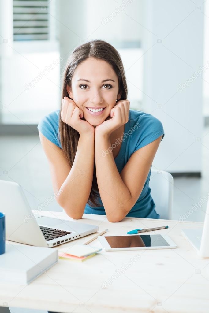 Smiling beautiful girl posing at desk