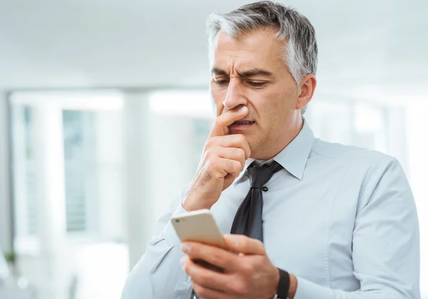 Confused businessman using a smart phone — Stock Photo, Image