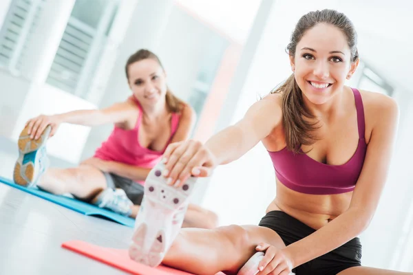 Gülümseyen kadın spor salonunda bacak germe — Stok fotoğraf