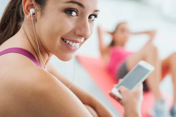 Jonge vrouw luisteren naar muziek op de sportschool — Stockfoto