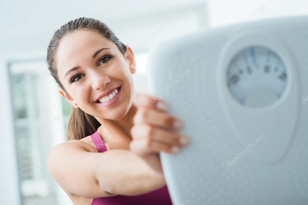 Happy woman showing a scale