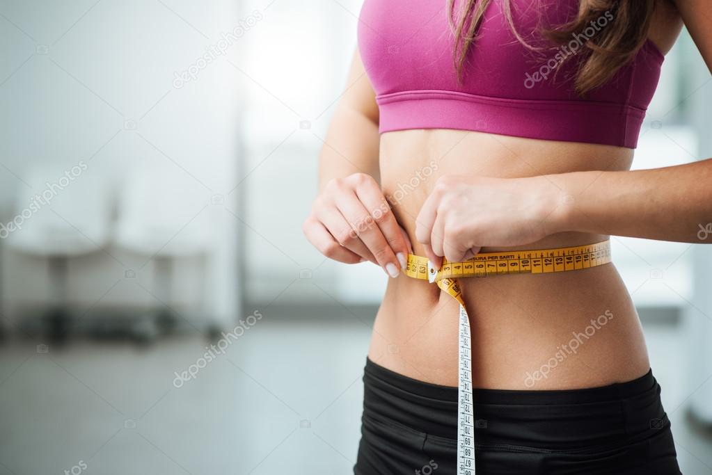 Slim woman measuring her thin waist