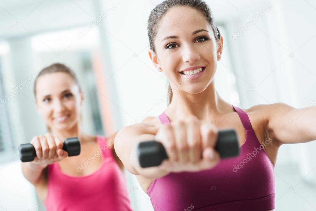 Sporty girls weightlifting at gym