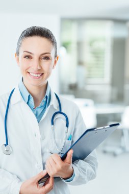 Tıbbi kayıtlarını tutan gülümseyen kadın doktor