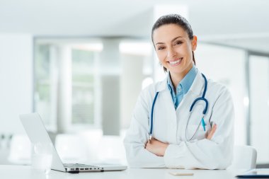 Confident female doctor at office desk clipart