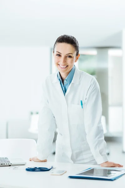 Confident female doctor leaning on desk — Stock Photo, Image