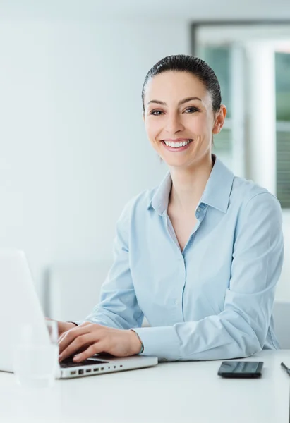 Smiling young businesswoman working at office desk — Stock Photo, Image