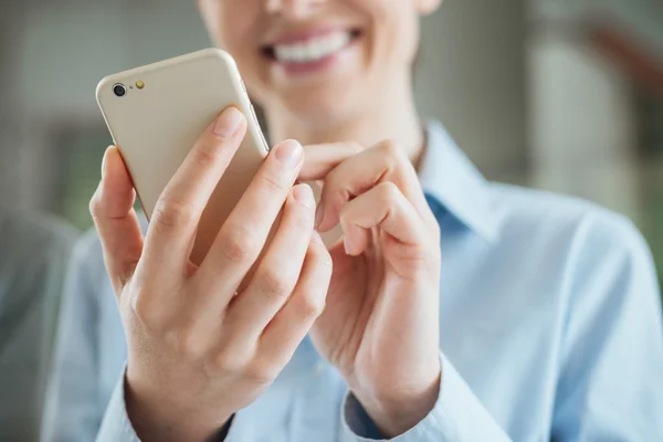 Mulher usando um smartphone e inclinando-se em uma janela — Fotografia de Stock