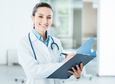 Tıbbi kayıtlarını tutan gülümseyen kadın doktor