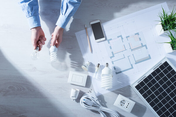Man comparing an incandescent bulb and a CFL lamp